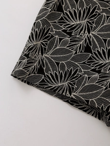 Detailed view of high-quality white leaf embroidery on black vintage fabric texture