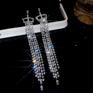 Detail of silver drop earrings with crown motif and long sparkling cubic zirconia tassels