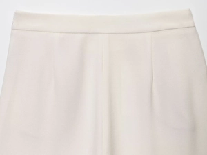 Detailansicht der cremeweißen gewebten Hose mit verdecktem Seitenreißverschluss und Nähten