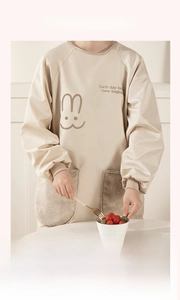 Detail of waterproof long sleeve apron featuring soft plush pocket and cute rabbit print