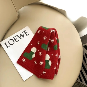 Detail of red knit scarf with green Christmas socks and white snowflake patterns on a chair