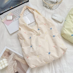 Close-up of cream canvas tote bag with 3D waffle texture and colorful bow embroidery