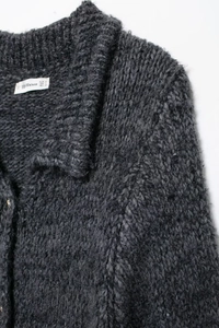 Détail du col en tricot et de l'étiquette de marque sur un cardigan en laine gris foncé