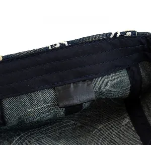 Detail of blue denim beret showing internal 100% cotton care label and neat stitching