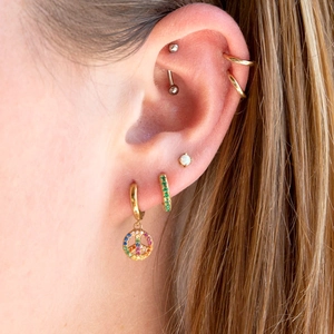 Rainbow zircon earrings set with peace sign charms and opal studs on a female ear