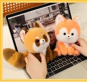 Close-up of soft red panda and fox plush toys on a laptop keyboard with detailed fur texture