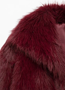 Gros plan détaillé du manteau en fausse fourrure bordeaux montrant la texture du col en poil