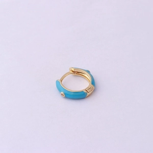 Detail of a gold huggie earring with blue enamel and small clear diamonds on purple background