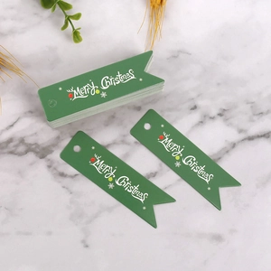 Dettaglio di etichette natalizie verdi a coda di rondine con scritta bianca Merry Christmas