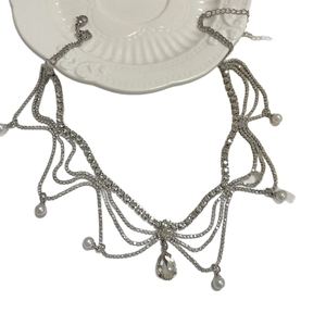 Silver fringe tassel necklace with rhinestones and teardrop pendant on a white tray