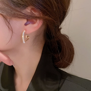 Close-up of gold-plated heart earrings with sparkling cubic zirconia on a female model