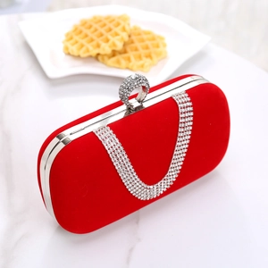 Detail of red velvet evening clutch featuring sparkling rhinestone tassel and u-shaped clasp