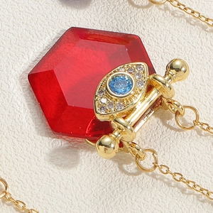 Detailed macro view of vintage red hexagonal crystal pendant with evil eye gold chain