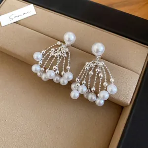 Detail shot of vintage pearl fringe earrings with silver bead tassels on brown leather