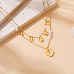 Gold layered stainless steel necklace with pearls and zircon heart pendant on stone