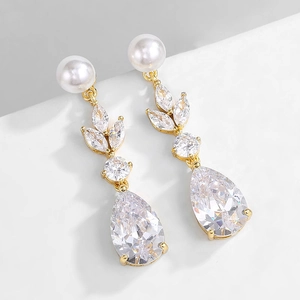 Detailed shot of gold drop earrings with leaf-shaped zircon and a white round pearl