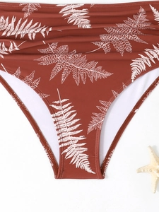 Dettaglio slip bikini a vita alta arancione bruciato con stampa di foglie bianche