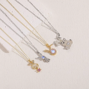 Elegant gold and silver rabbit necklaces with zircon and gemstones on a white stone base