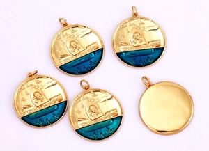 Macro view of gold round pirate ship charms with blue oil drip finish for DIY jewelry