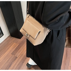 Detail of khaki corduroy shoulder bag showing texture, metal buckle, and zipper closure