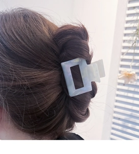 Detailed view of a square acetate hair claw clip in pearlescent blue and white tones