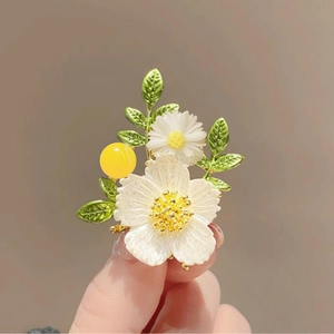 Elegant white flower brooch with green enamel leaves and yellow bead in a golden finish