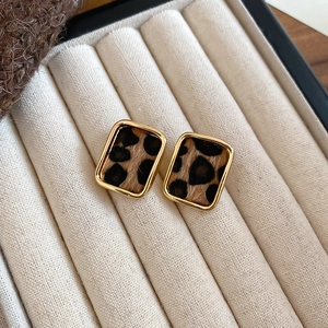 Detailed close-up of leopard print fabric earrings set in gold rectangular metal frames