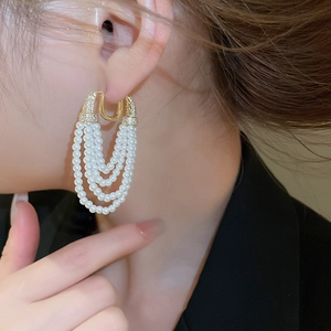 Vue détaillée de boucles d'oreilles dorées à pampilles de perles et zircons sur un mannequin