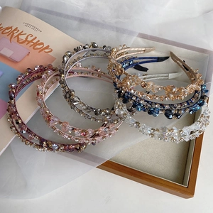 Close-up of handmade crystal and pearl beaded headbands in a wooden tray