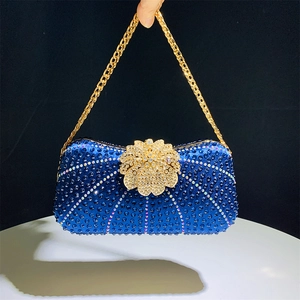 Detail of luxury royal blue rhinestone evening bag with floral clasp and gold chain strap