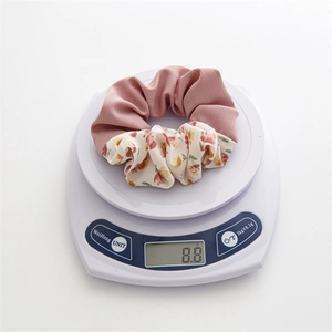 Floral and pink fabric hair scrunchie weighing 8.8g on a digital scale for light comfort