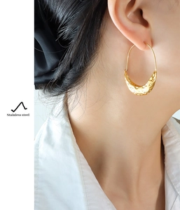 Macro detail of boat-shaped hammered 18K gold plated stainless steel hoop earrings