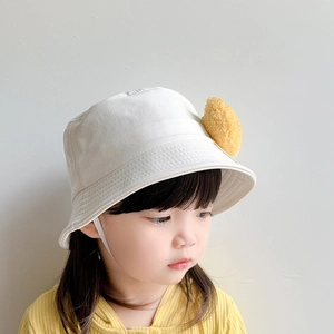Detail of cream kids bucket hat with yellow pom-pom and windproof chin strap