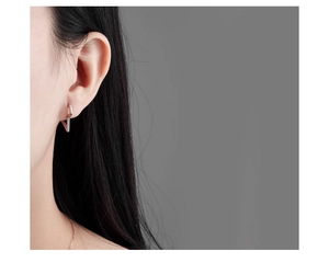 Close-up of minimalist silver lightning bolt earring worn by a female model
