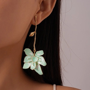 Detail of mint green enamel flower earring with gold curved stem on a model's ear