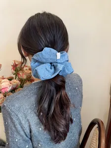 Detailed view of light blue polka dot scrunchie with a Hand Made label on soft hair