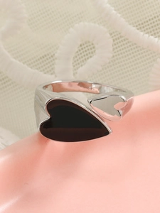 Detailed macro of silver heart ring with black enamel drip design on lace backdrop