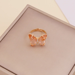 Detail of gold butterfly ring with pink and orange gemstones on a soft jewelry box