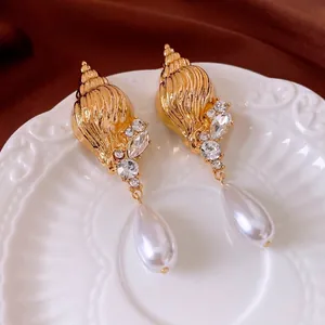 Vintage shell drop earrings with sparkling rhinestones and teardrop pearls on a white tray