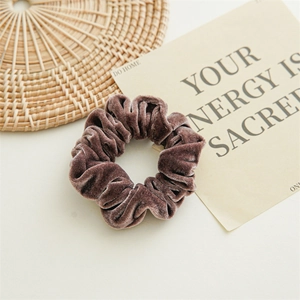 Detail of brown velvet scrunchie on woven mat with aesthetic card for hair styling
