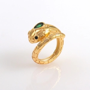 Dettaglio macro di anello a serpente dorato con gemma verde e cristalli micro pavé