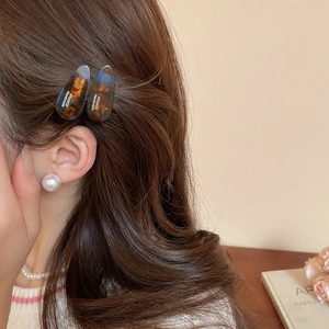 Détail de pinces à cheveux ovales en acrylique écaille avec lettrage doré fait main
