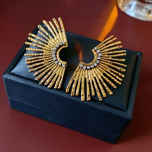 Macro shot of gold fan-shaped earrings with textured metal and sparkling rhinestones
