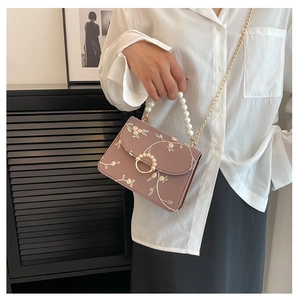 Detail of lavender floral embroidered bag with white pearl handle and gold chain strap