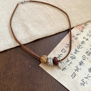 Macro detail of a vintage necklace with wooden beads and a hammered silver pendant