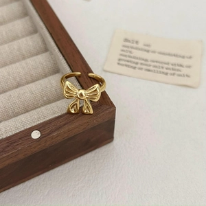 Close-up of golden bow-shaped adjustable S925 silver ring on a wooden jewelry box