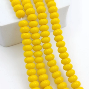 Vertical view of bright yellow 8x5mm glass abacus beads hanging on white stone decor