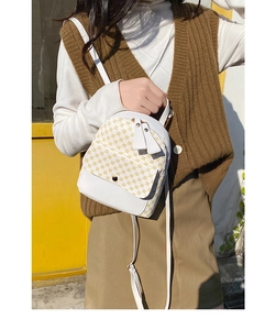 Detail view of mini white backpack with yellow pattern and adjustable shoulder straps