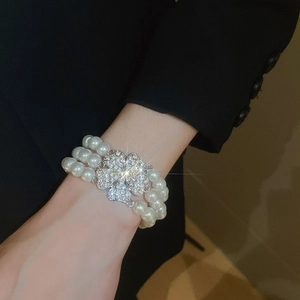 Close-up of multilayer pearl bracelet with a sparkling silver clover diamond clasp