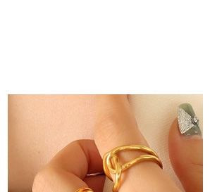 Close-up of a double-layered gold knotted ring with micro-set cubic zirconia on a finger